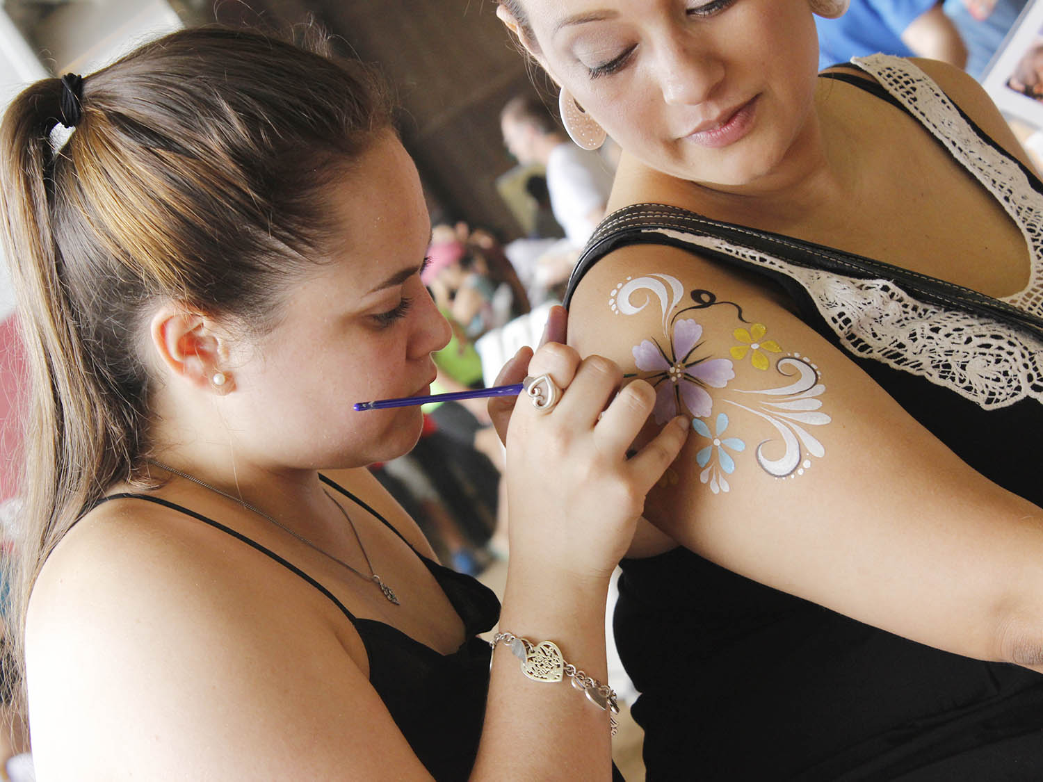 Artist applying paint to customer's arm.